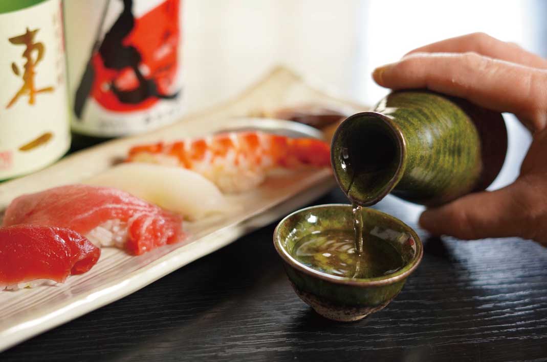 寿司の横で日本酒をつぐ